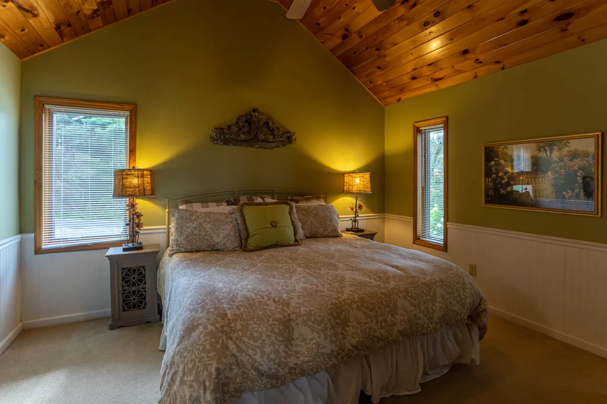 This image features a cozy bedroom with a comfortable bed, wall lamps that provide soft lighting for reading, and tasteful decorative wall art. The mood is peaceful and inviting, evoking a sense of restful retreat—ideal for showcasing a master suite or a serene king bedroom.