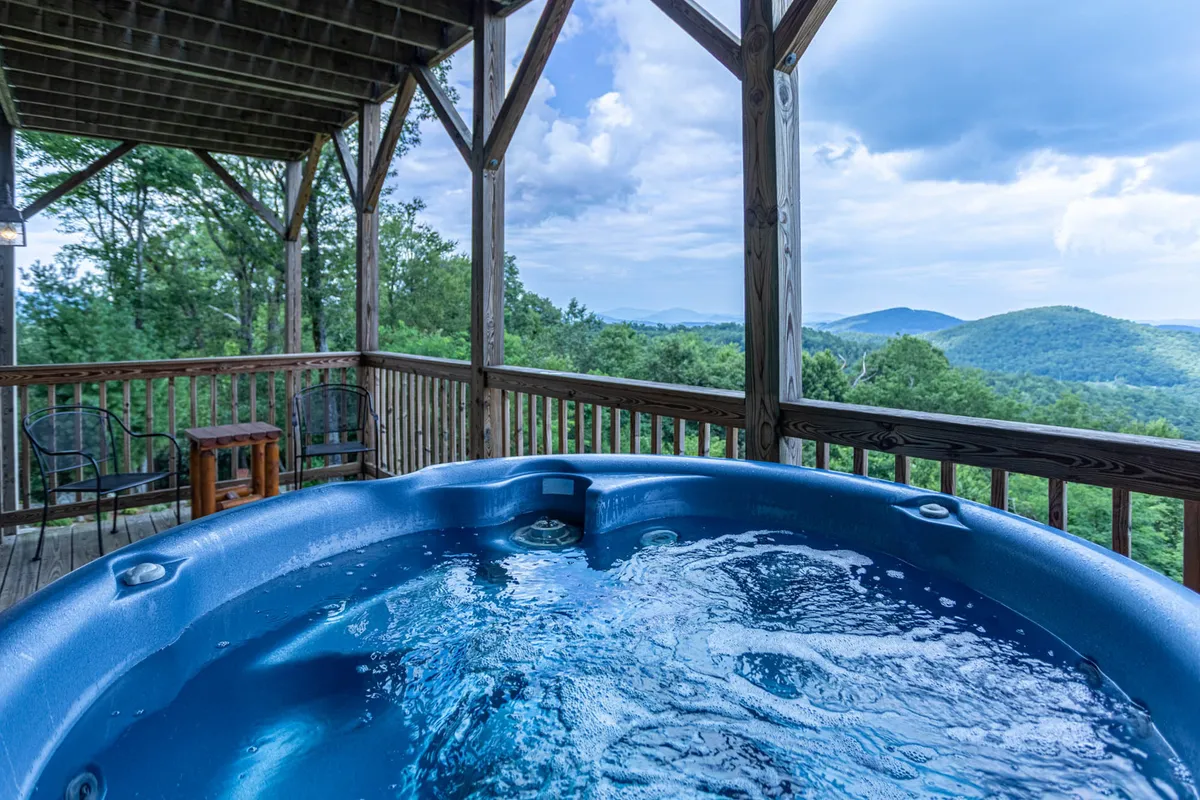 This image captures a tranquil wooden deck with a private hot tub overlooking expansive mountain views. The setting is perfect for relaxing outdoors, soaking in the hot tub, or enjoying the sunset and stargazing. The deck's position offers an immersive experience of the changing mountain scenery throughout the year.