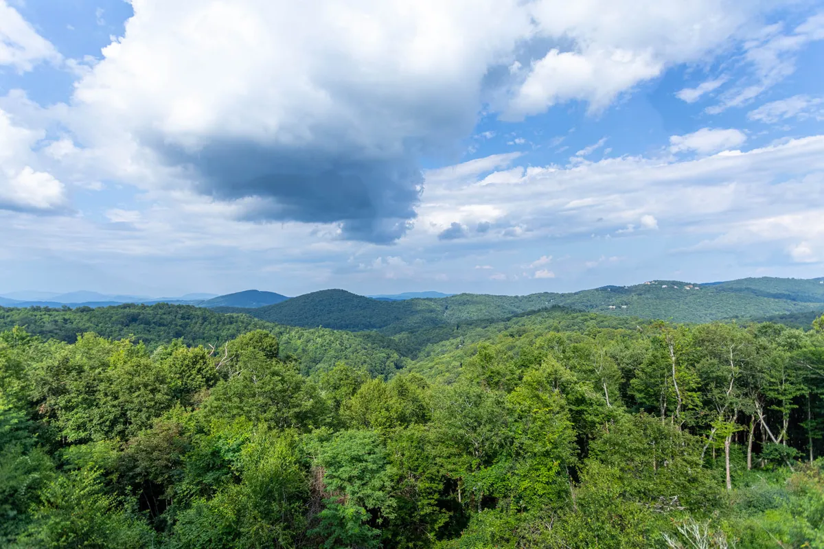 A stunning view of the Blue Ridge Mountains featuring rolling hills, lush greenery, and dramatic cloud formations. The expansive landscape is ideal for hiking, photography, and simply taking in the beauty of nature in any season.